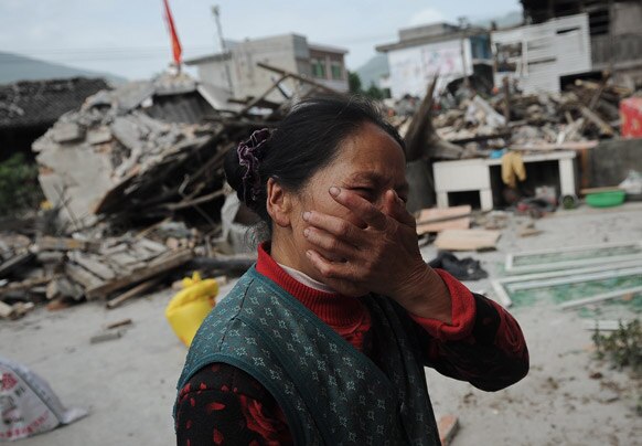 चीनमधील  भूकंपात शिचुआना प्रांतातील एका गावात घर पडल्यानंतर अश्रु अनावर झालेली महिला