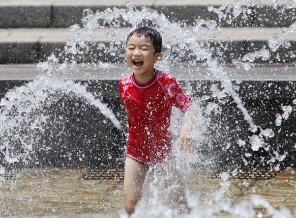 टोक्यो पार्कमध्ये पाण्यात खेळणारा मुलगा