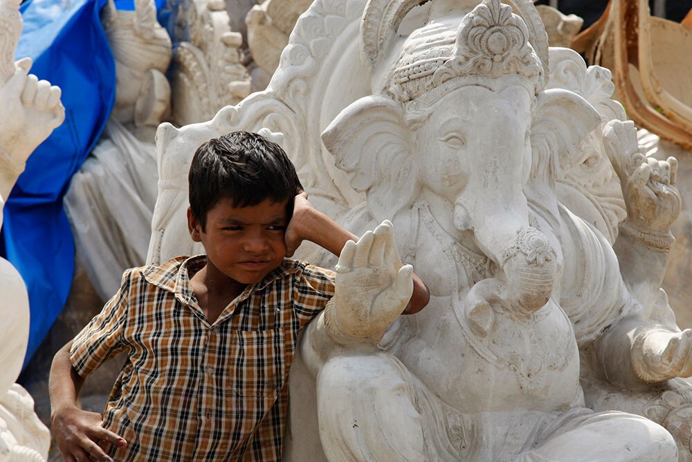 हैदराबाद येथे गणेश मूर्तीच्या कारखान्यात उभा असलेला मुलगा.