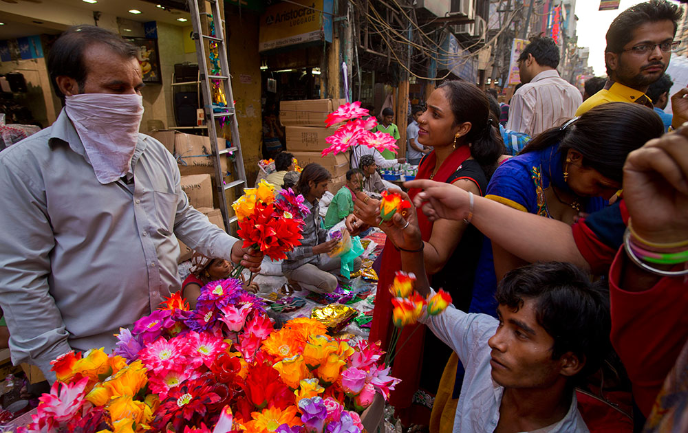 नवी दिल्लीत प्लास्टीकचे फूल विकत घेताना महिला. 
