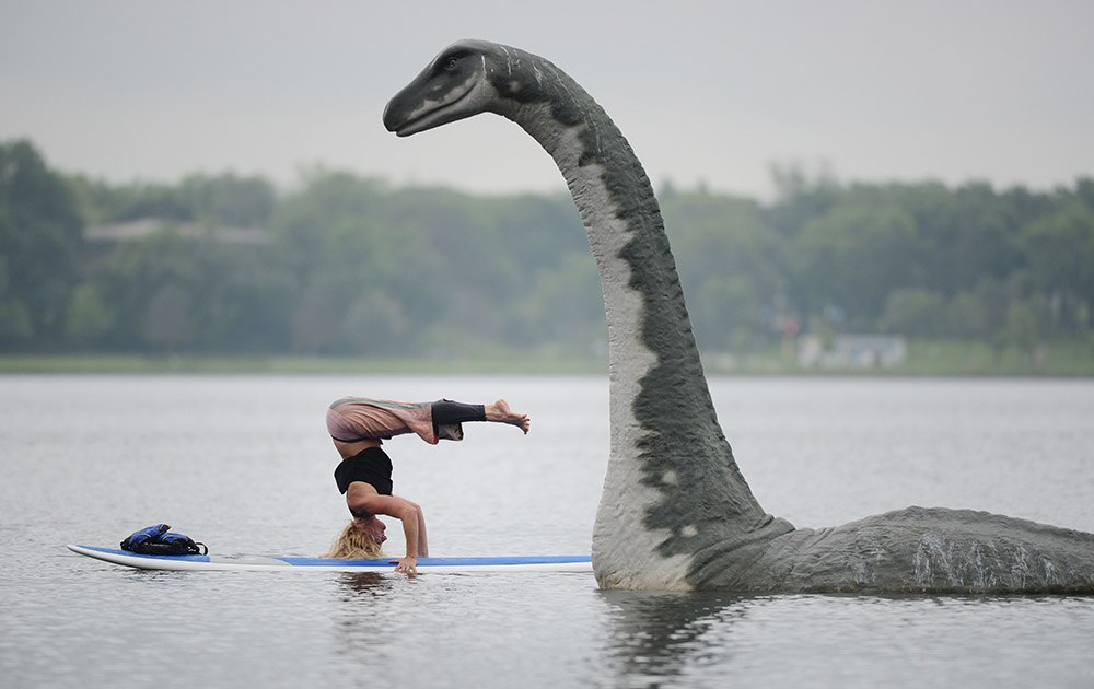 आंतरराष्ट्रीय योगदिन! - Stachia Fey, of the Wai Nani Surf and Paddle Tribe, strikes a yoga pose on her paddle board next to Minne, a 13' fiberglass lake creature on Lake Calhoun in Minneapolis, Minn.
