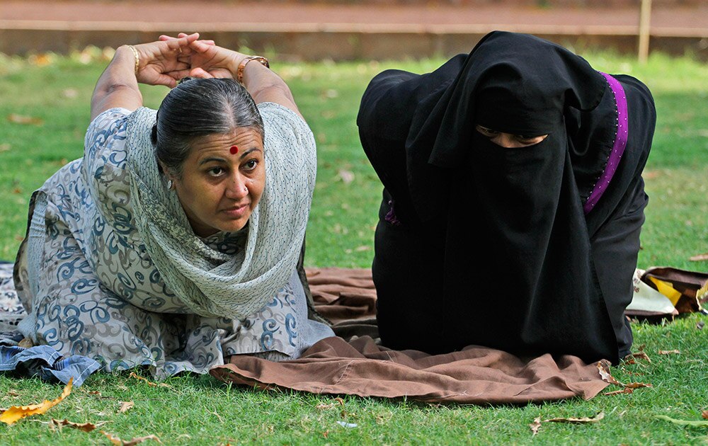 आंतरराष्ट्रीय योगदिन! Yoga trainer Chandrikaben Kansara teaches yoga to a Muslim woman in a garden in Ahmadabad. Yoga has a long history India, reaching back for thousands of years. The government of Prime Minister Narendra Modi has made clear it wants the first International Yoga Day, held on Sunday, June 21, 2015, to be taken seriously.
