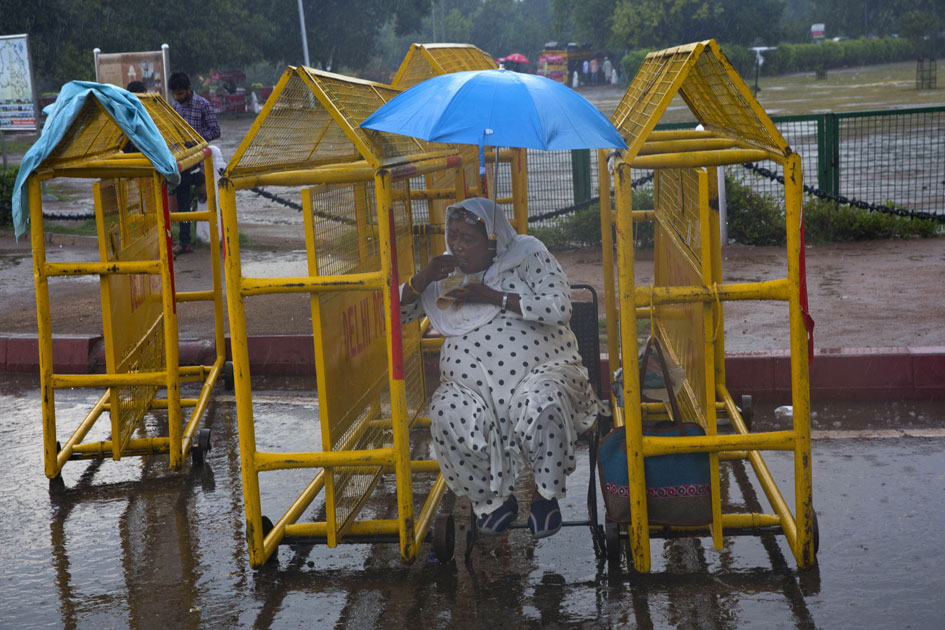 Indian woman eats a snack sitting in between police barricades