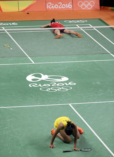 Spain`s Carolina Marin, top, lies on the court