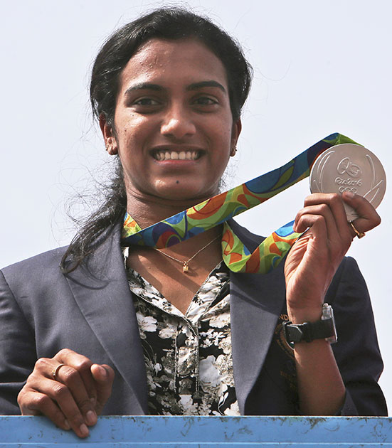 Pusarla Sindhu displays her silver medal as she is brought home in a procession upon their arrival at Hyderabad