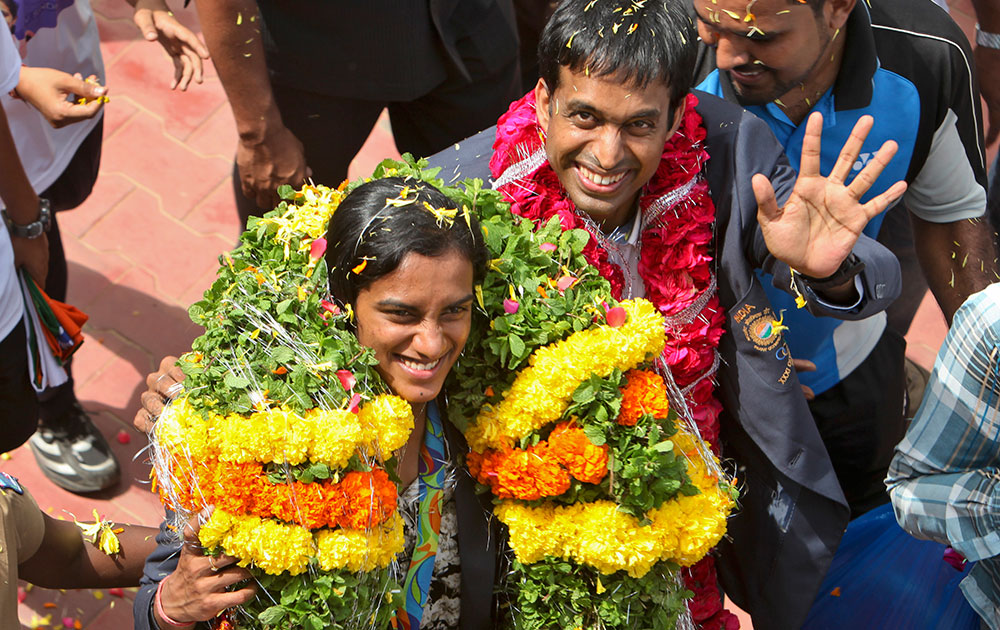 P.V. Sindhu and her coach Pullela Gopichand wave to the cameras during their reception at the Gopichand Academy in Hyderabad