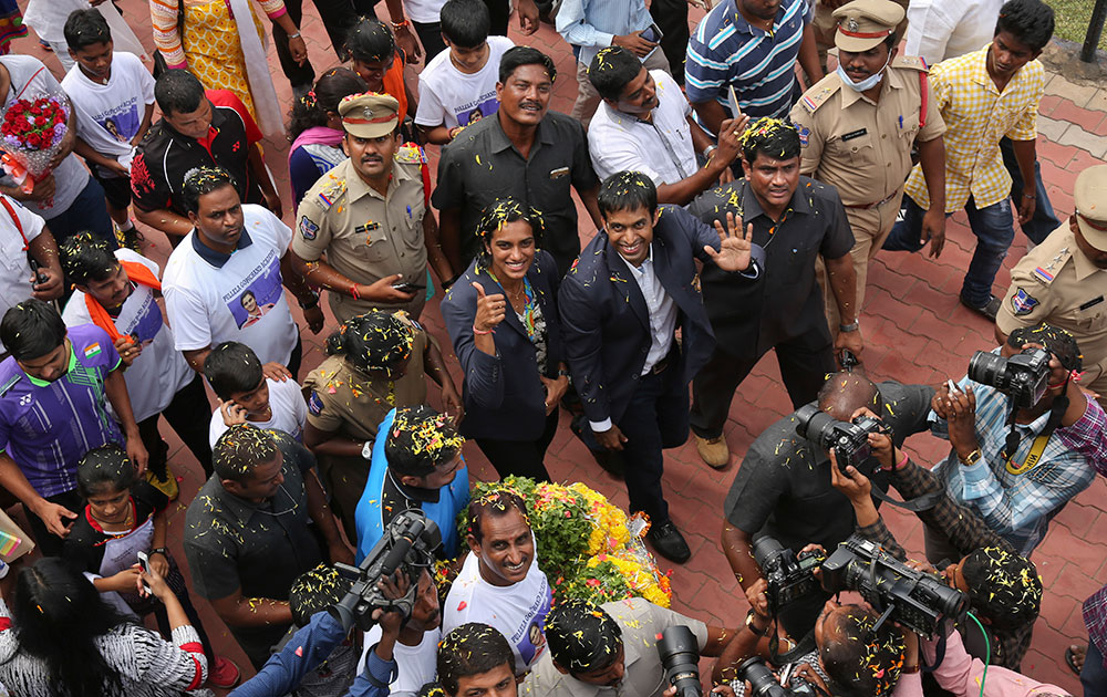 P.V. Sindhu and her coach Pullela Gopichand wave to the cameras during their reception at the Gopichand Academy in Hyderabad