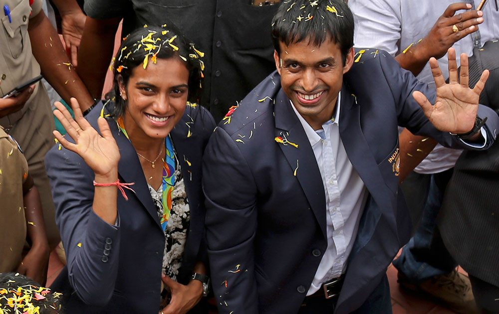 P.V. Sindhu and her coach Pullela Gopichand wave to the cameras during their reception at the Gopichand Academy in Hyderabad