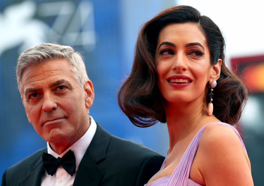 Actor and director George Clooney and his wife Amal pose during a red carpet