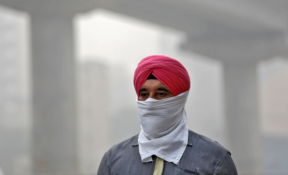Man covers his face as he walks to work in Delhi.