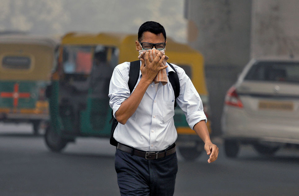 Man covers his face as he walks to work in Delhi.