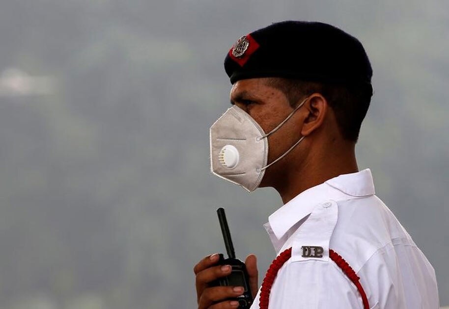 A traffic policeman wearing a mask controls the traffic at a busy road on a smoggy morning in New Delhi.