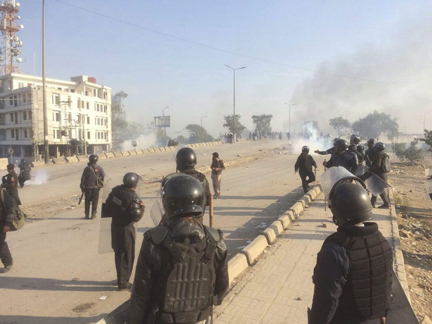 Smoke rises as Pakistani police officers fire tear gas shell to disperse protesters during a clash in Islamabad, Pakistan.