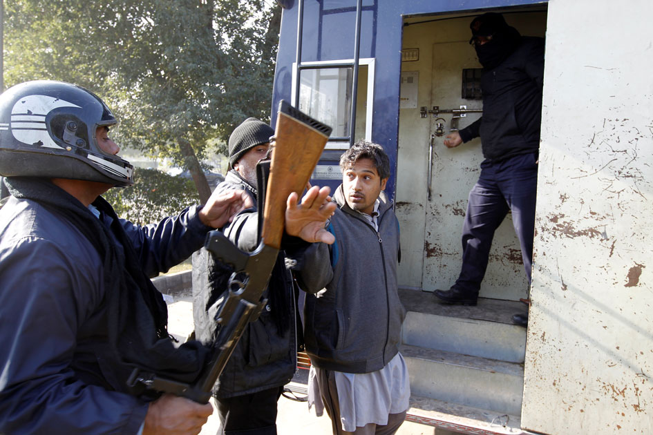 A demostrator detained by police gestures after being hit by a policeman as he is led to a police van near the Faizabad junction in Islamabad.