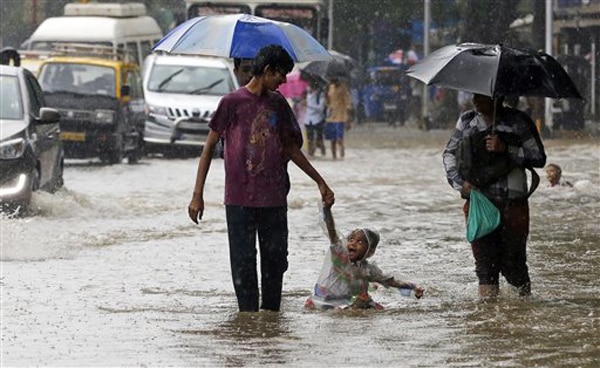 मुंबई पावसाने धुमाकूळ घातल्याने सखल भागात साचलेल्या पाण्यातून वाट काढताना